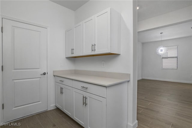 kitchen featuring baseboards, white cabinets, light countertops, wood tiled floor, and pendant lighting