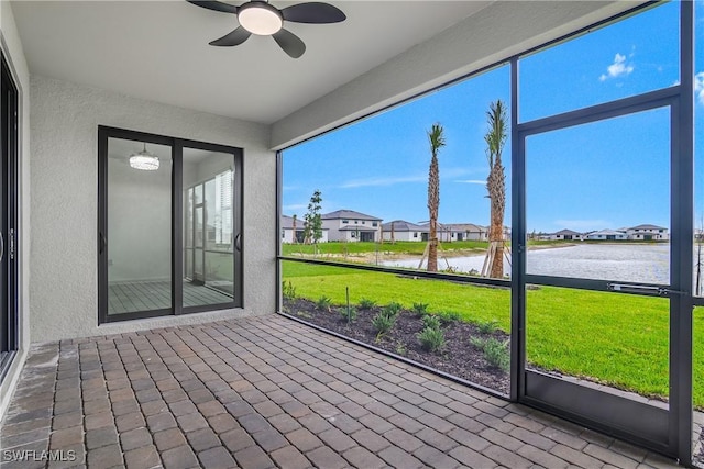 unfurnished sunroom featuring a residential view, a water view, and ceiling fan