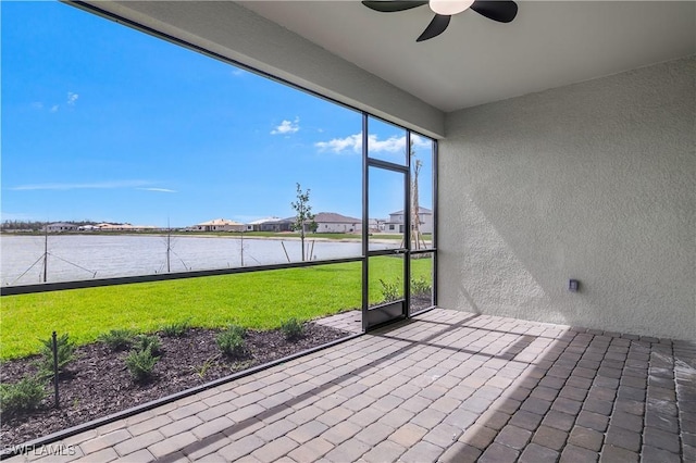 unfurnished sunroom featuring a water view, a healthy amount of sunlight, and a ceiling fan