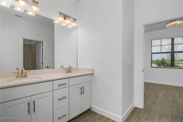 bathroom with double vanity, wood finished floors, a sink, and baseboards