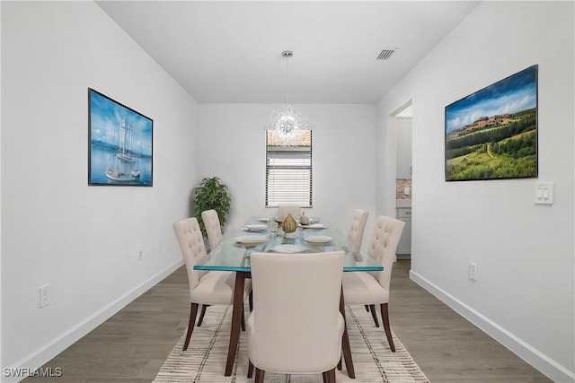 dining room with baseboards, visible vents, a chandelier, and wood finished floors