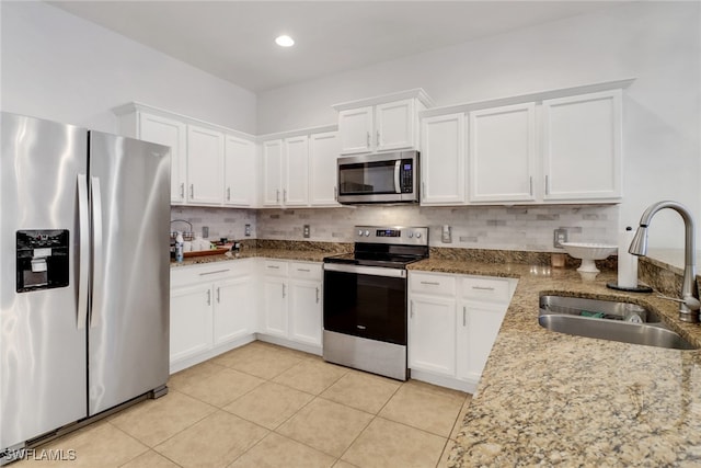 kitchen featuring appliances with stainless steel finishes, white cabinets, a sink, and decorative backsplash