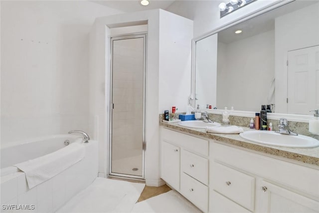 bathroom featuring a bath, a stall shower, double vanity, and a sink