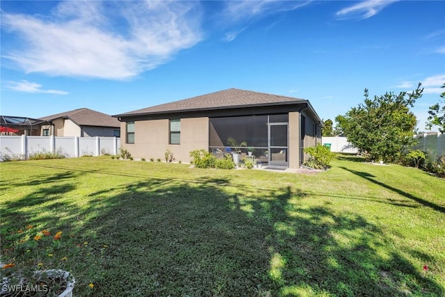 rear view of house with a yard, a fenced backyard, a sunroom, and stucco siding