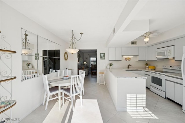 kitchen featuring light countertops, visible vents, a sink, white appliances, and a peninsula