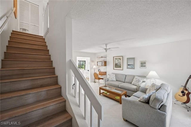 living room with stairs, ceiling fan, light tile patterned floors, and a textured ceiling