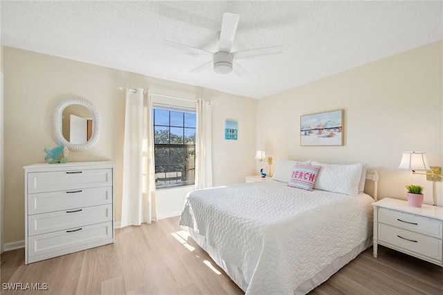 bedroom with light wood-style floors, a textured ceiling, baseboards, and a ceiling fan