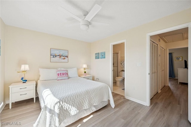 bedroom featuring light wood finished floors, attic access, baseboards, ceiling fan, and ensuite bathroom