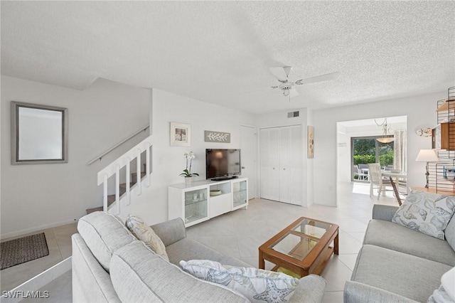 living room with light tile patterned floors, stairs, visible vents, and a textured ceiling