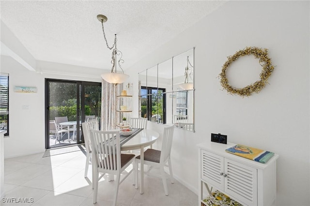 dining area with a textured ceiling, plenty of natural light, light tile patterned flooring, and baseboards