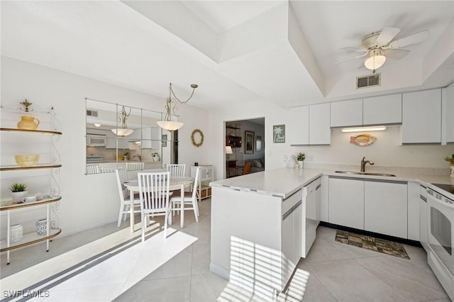 kitchen with a peninsula, visible vents, a sink, and light tile patterned flooring