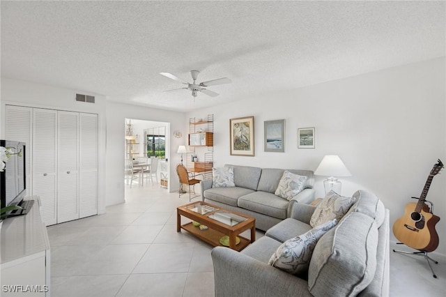 living area with visible vents, ceiling fan, a textured ceiling, and light tile patterned flooring