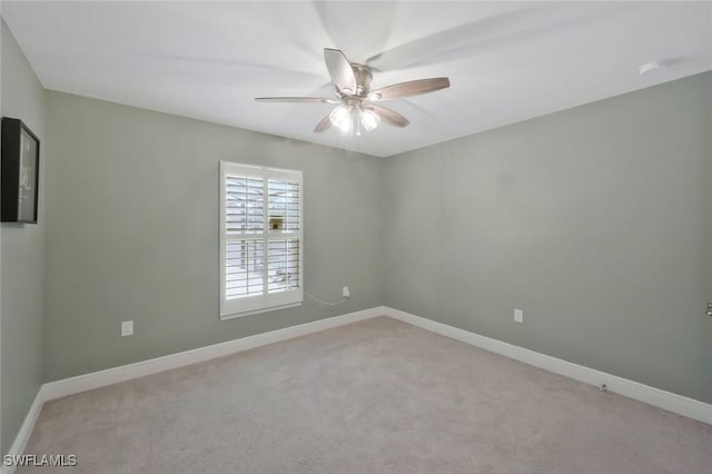 spare room featuring light carpet, baseboards, and a ceiling fan