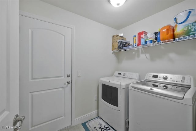 clothes washing area with laundry area, baseboards, and washing machine and clothes dryer