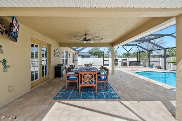 view of patio with outdoor dining space, glass enclosure, fence, and ceiling fan