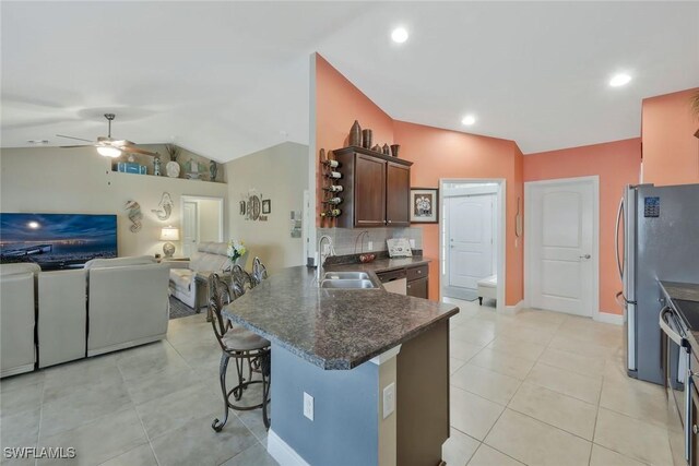 kitchen featuring lofted ceiling, stainless steel appliances, a breakfast bar, a peninsula, and a sink