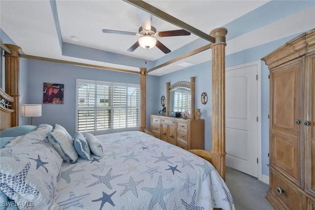 carpeted bedroom with a raised ceiling and a ceiling fan