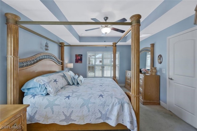 bedroom featuring carpet floors, a tray ceiling, a ceiling fan, and baseboards