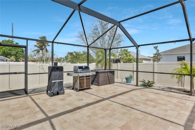 view of patio / terrace featuring glass enclosure, area for grilling, and a fenced backyard