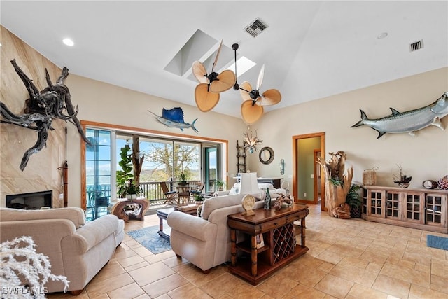 living area featuring a premium fireplace, visible vents, a skylight, and a ceiling fan