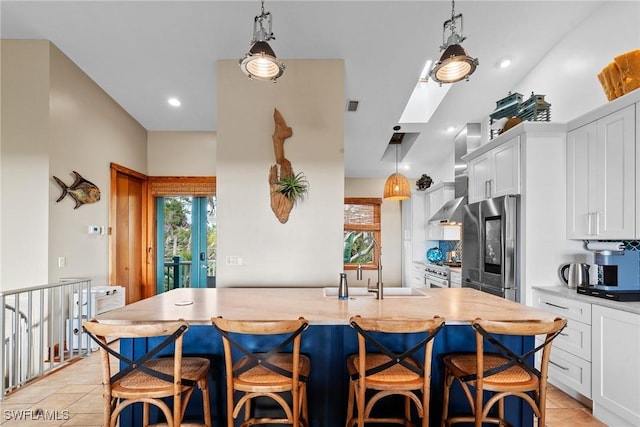 kitchen with white cabinetry, wall chimney exhaust hood, a healthy amount of sunlight, and appliances with stainless steel finishes