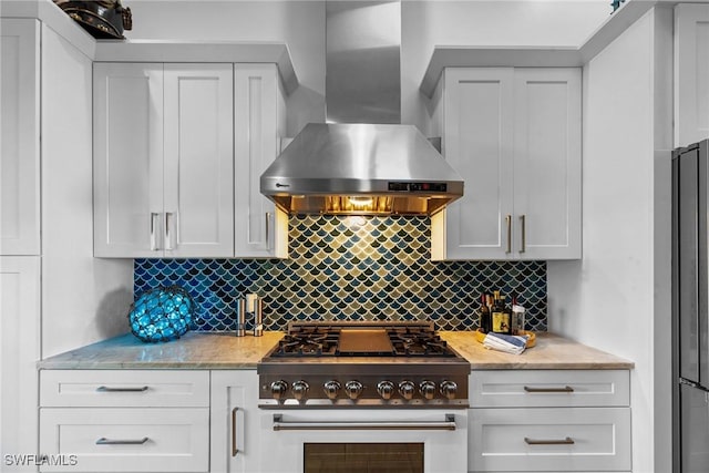 kitchen featuring stainless steel stove, backsplash, wall chimney exhaust hood, and light stone countertops