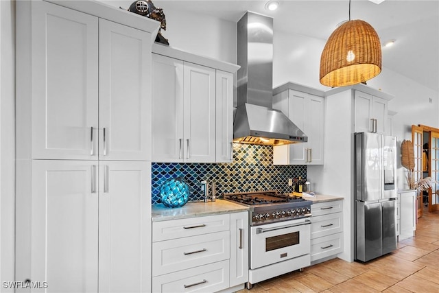 kitchen with stainless steel refrigerator with ice dispenser, backsplash, gas range oven, white cabinets, and wall chimney range hood