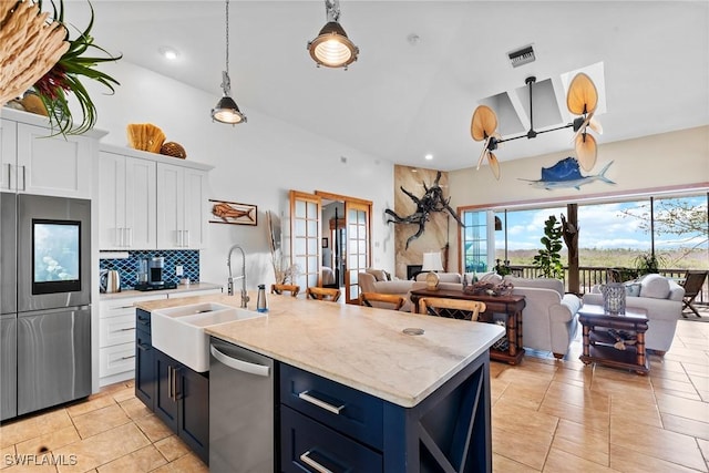 kitchen with a sink, open floor plan, white cabinetry, stainless steel appliances, and decorative backsplash