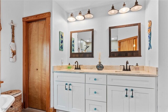 full bathroom with double vanity, a tub, and a sink