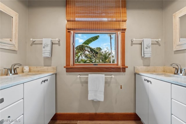 bathroom with two vanities, baseboards, and a sink