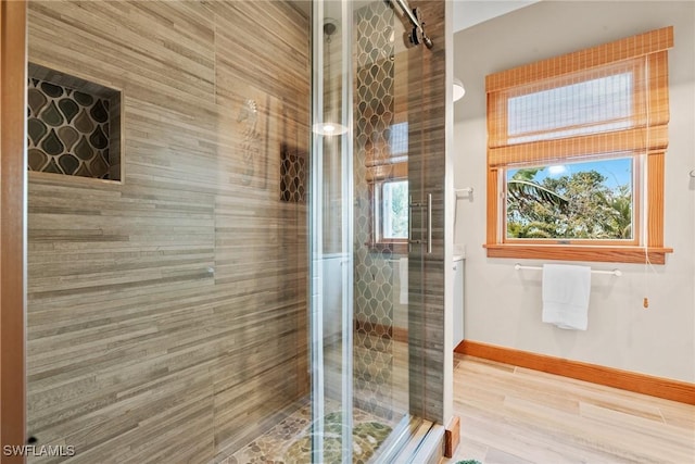 bathroom with wood finished floors, baseboards, and a stall shower