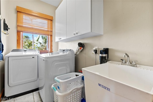 washroom featuring washing machine and clothes dryer, light tile patterned floors, cabinet space, and a sink