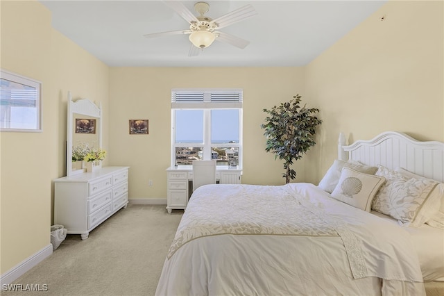 bedroom featuring light carpet, multiple windows, a ceiling fan, and baseboards