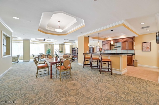 dining area with baseboards, visible vents, a raised ceiling, and crown molding