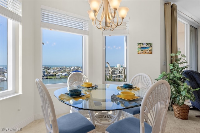 carpeted dining room featuring a chandelier, a water view, and baseboards