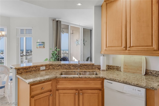 kitchen with white dishwasher, light stone counters, and a sink