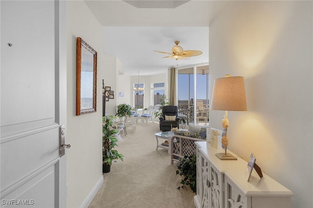 hallway with baseboards, a chandelier, and light colored carpet