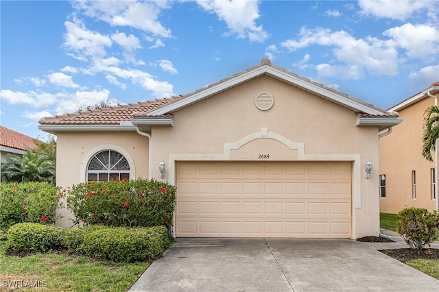 mediterranean / spanish-style house featuring a garage, a tiled roof, driveway, and stucco siding