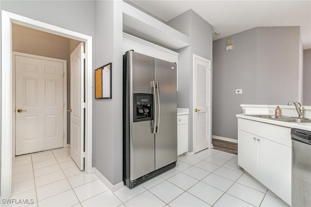 kitchen with appliances with stainless steel finishes, light countertops, a sink, and light tile patterned flooring