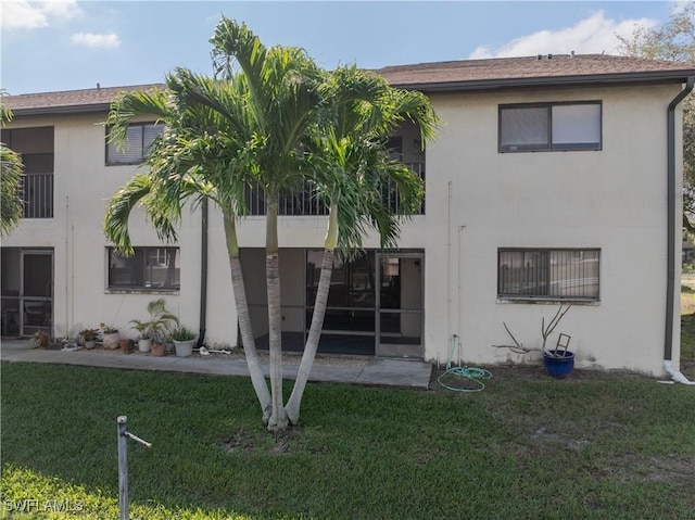 rear view of property with a yard, a patio, and stucco siding