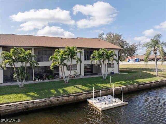 rear view of house with a water view, stucco siding, and a yard