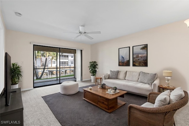 living area featuring baseboards, a ceiling fan, and carpet flooring