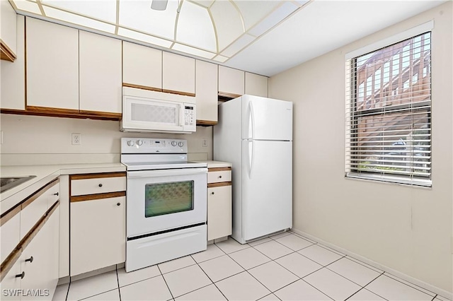 kitchen with light tile patterned floors, white appliances, light countertops, and white cabinetry