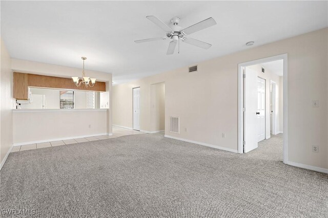 unfurnished living room featuring light carpet, ceiling fan with notable chandelier, visible vents, and baseboards