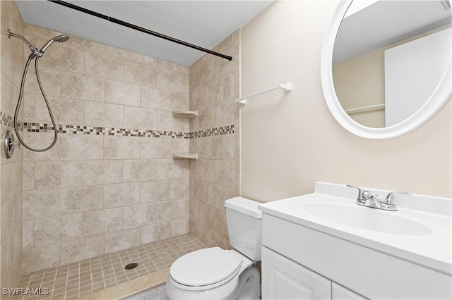 bathroom with tiled shower, vanity, and toilet