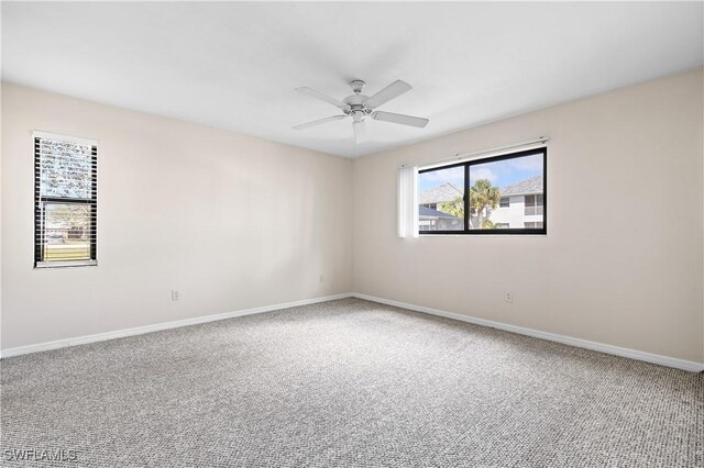 carpeted empty room featuring a ceiling fan and baseboards