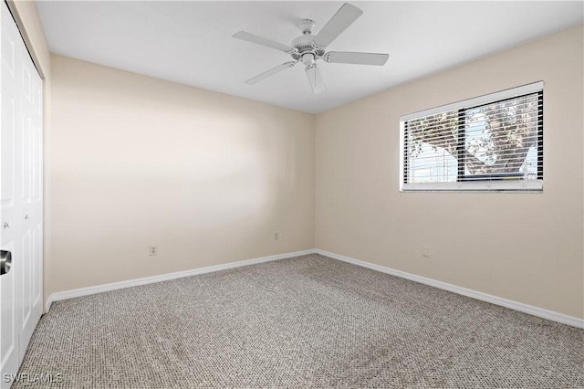 carpeted spare room with baseboards and a ceiling fan