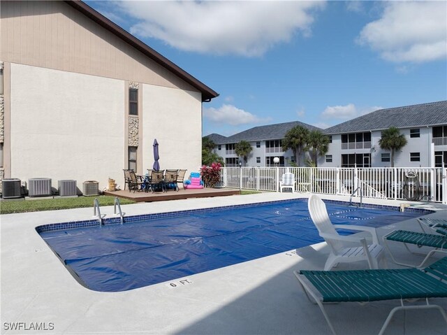 pool with central AC unit, a patio area, and fence