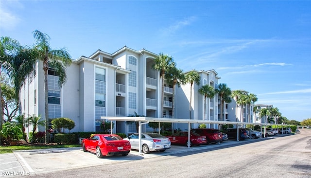 view of building exterior with covered and uncovered parking