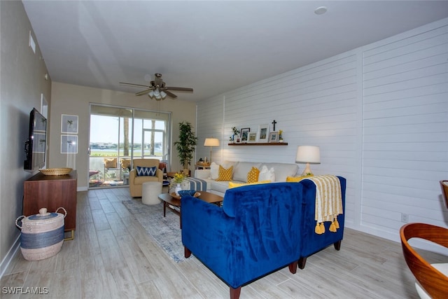 living area featuring ceiling fan, baseboards, and wood finished floors